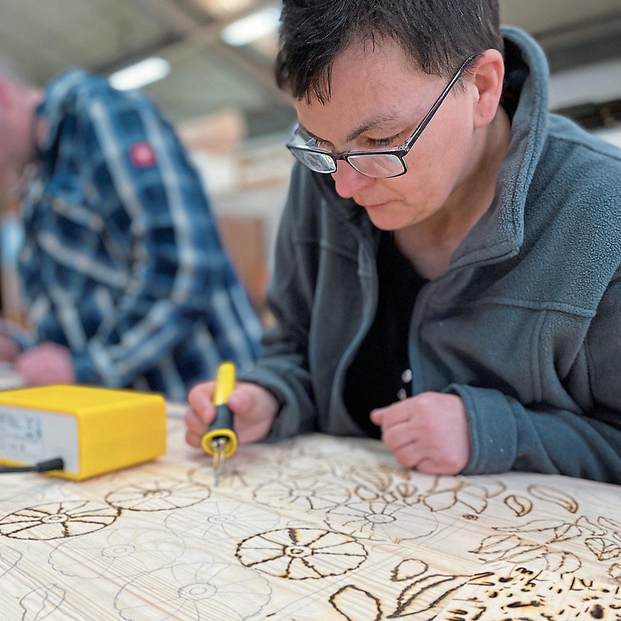 Die Beschäftigten von Spectrum verzieren den Anker mit Ornamenten, die sie einbrennen.